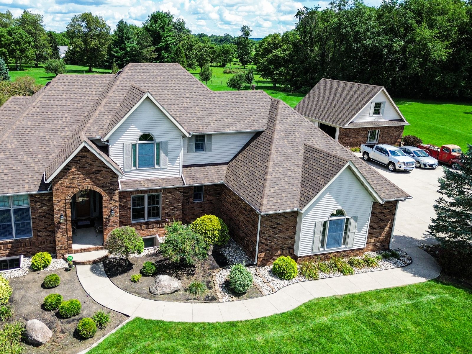 Wide aerial of the finished brown GAF roof with the detached carriage building beyond — Bellefontaine, Ohio