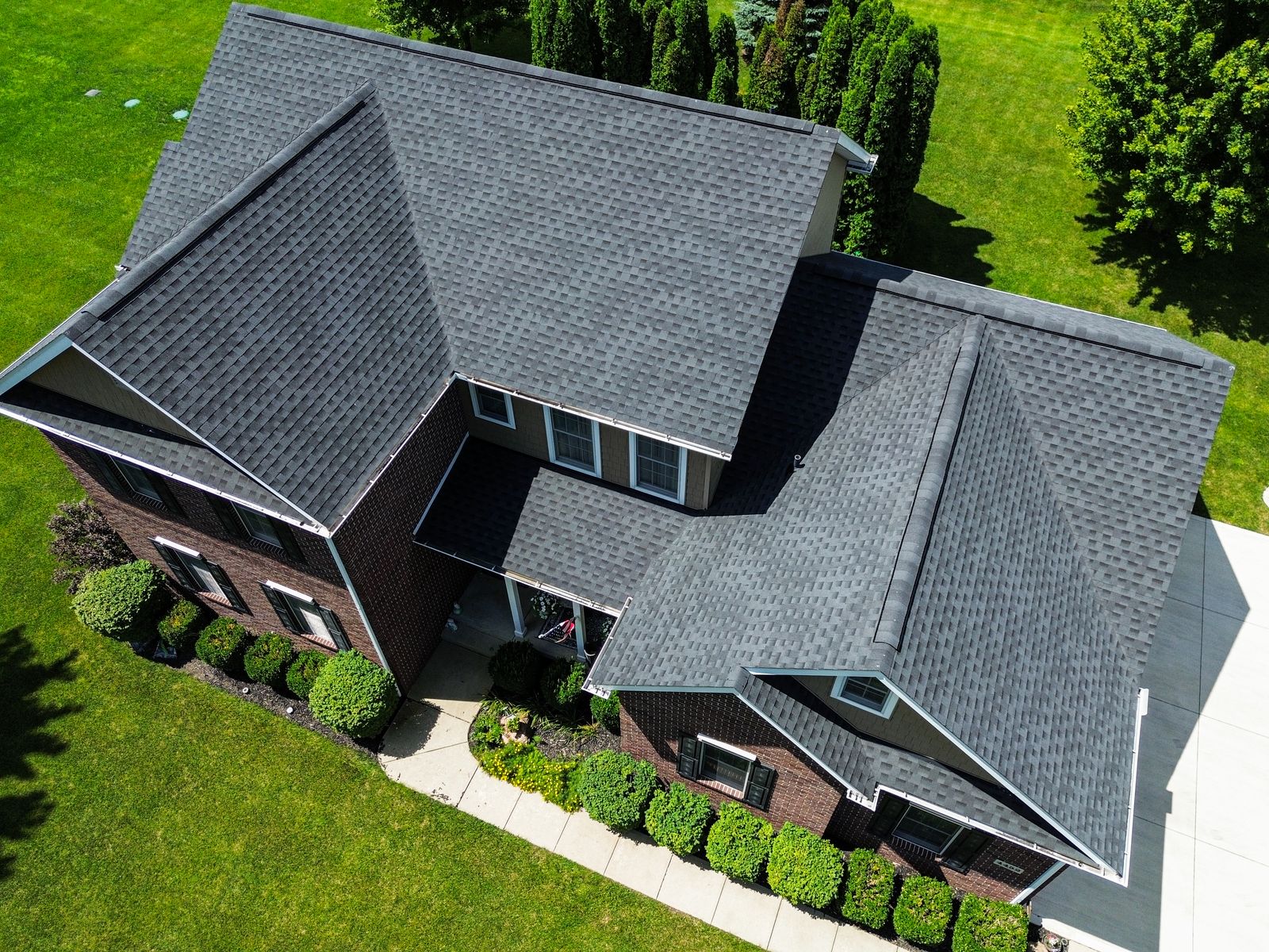 Oblique aerial of the Charcoal GAF roof against dark brick and evergreen screen — Bellefontaine, Ohio