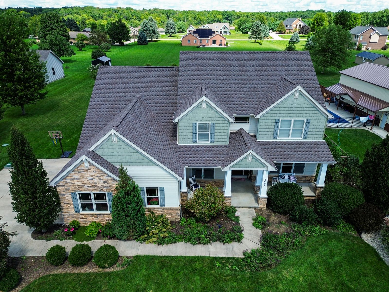 Completed GAF Timberline HDZ roof on a Craftsman home with sage shake gables, stone veneer and a columned front porch — Bellefontaine, Ohio