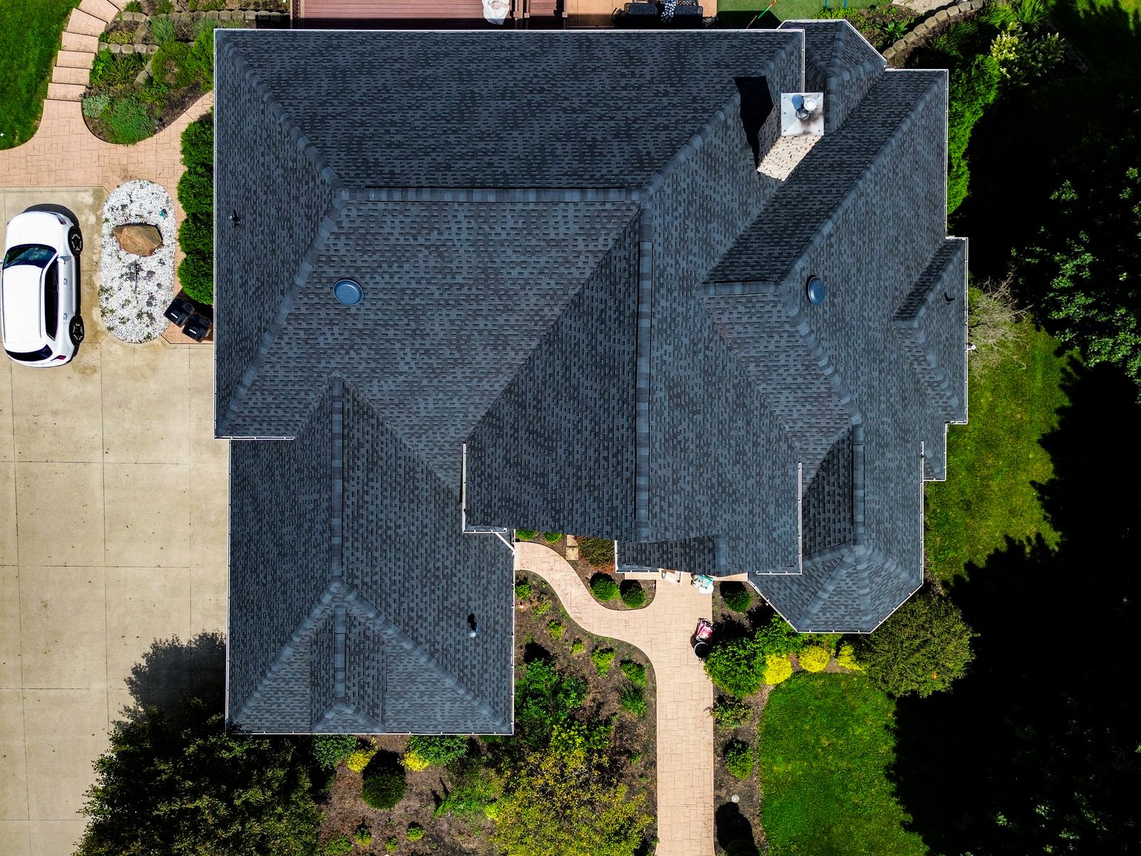 Top-down aerial of a completed dark architectural shingle roof with octagonal turret and multiple hip planes — Bellefontaine, Ohio