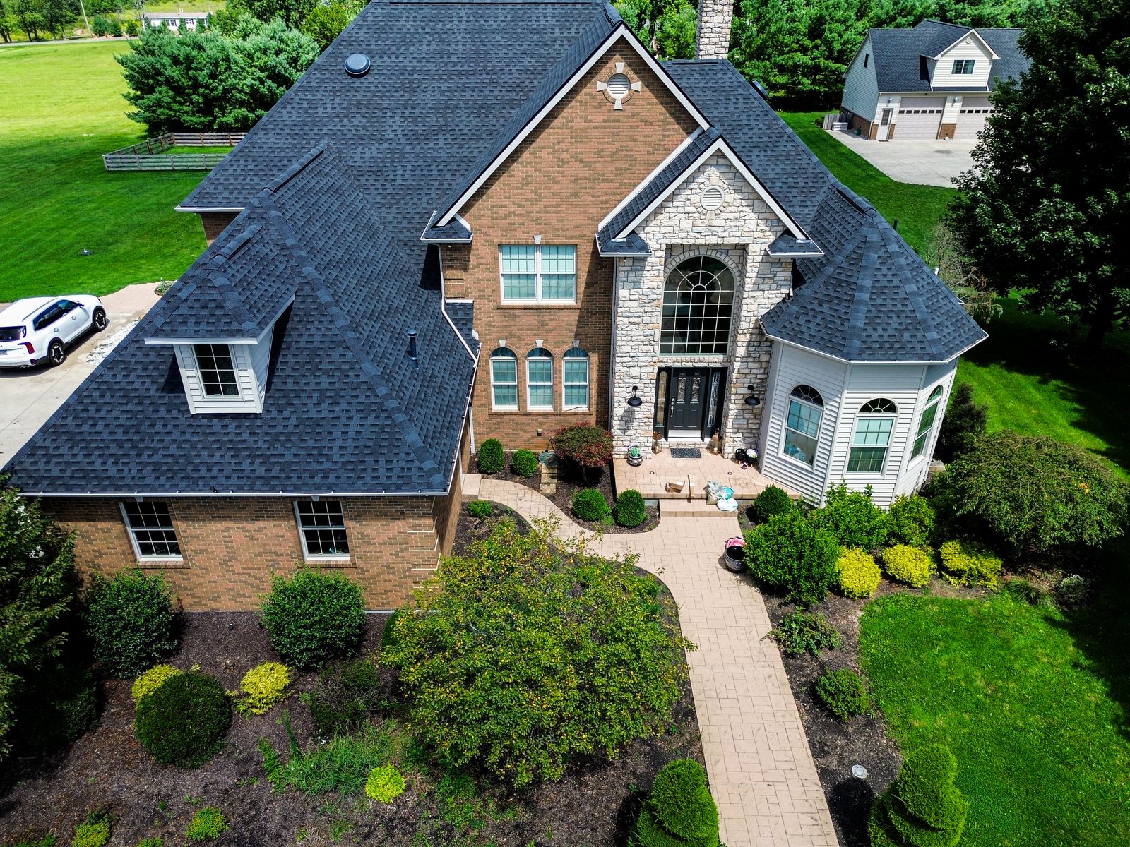 Wide aerial of the finished dark GAF roof on a brick-and-stone home with detached garage — Bellefontaine, Ohio