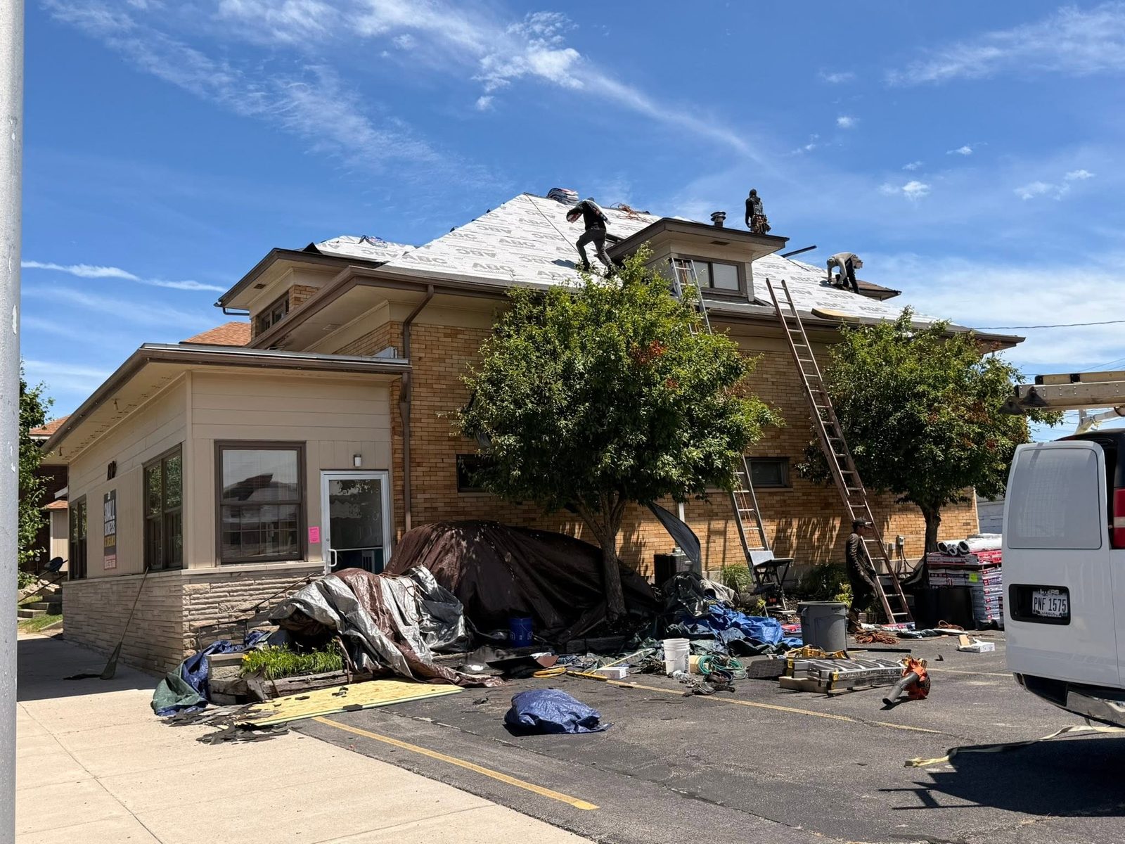 Roofing crew working a dormer with the roof dried in under ABC ProGuard underlayment — downtown Bellefontaine, Ohio