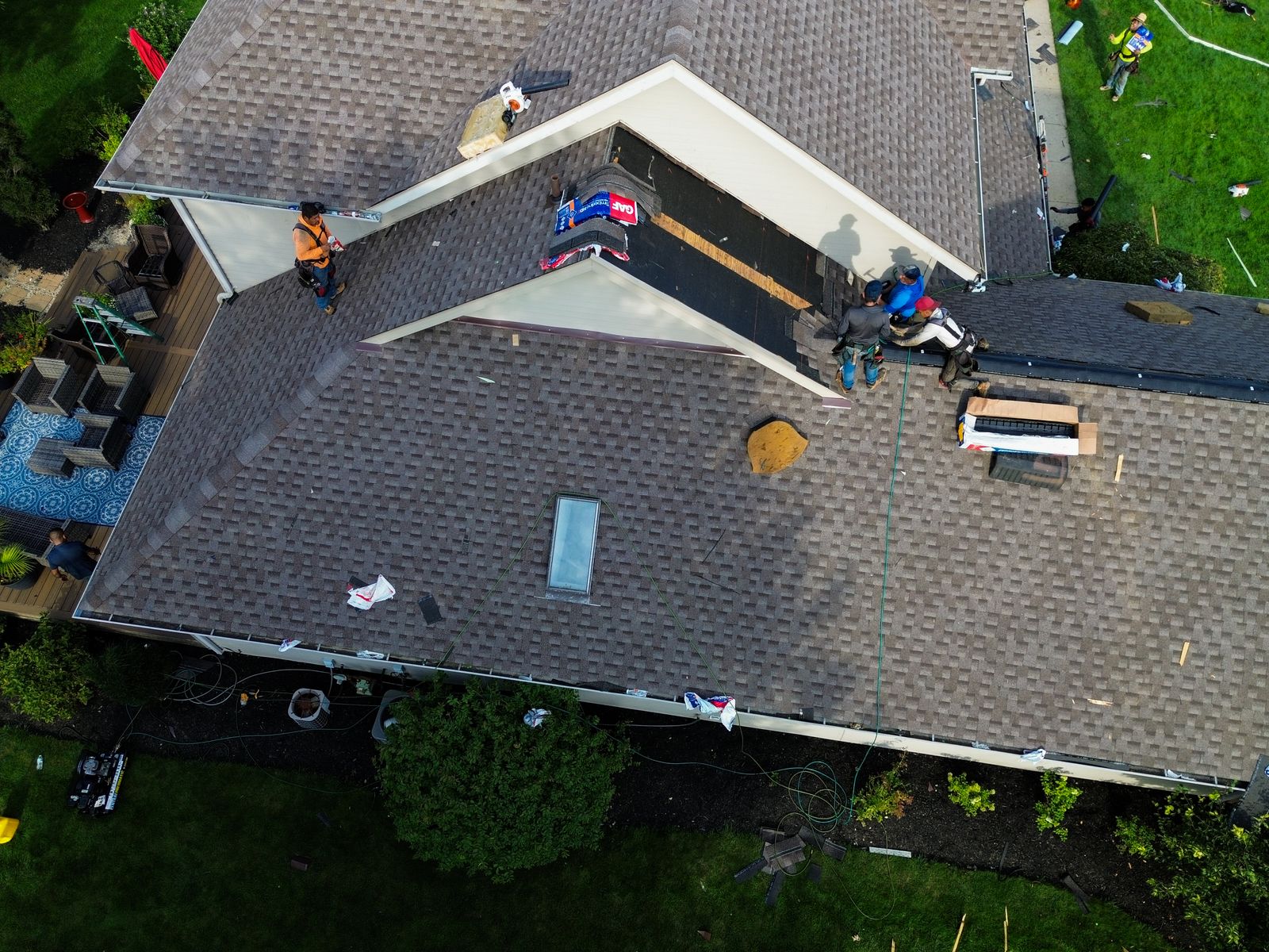 Front gable stripped back to bare sheathing during a roof replacement, crew working the ridge — Hardin County, Ohio