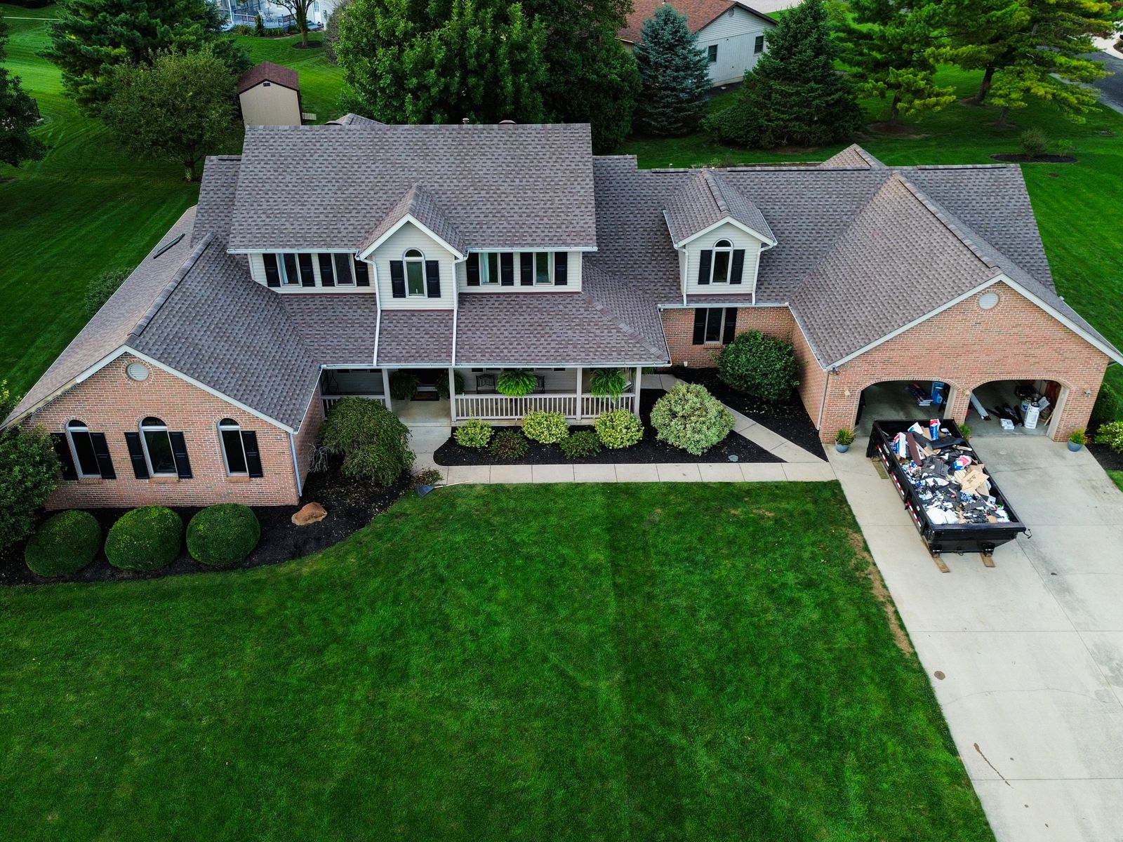 Completed GAF Timberline HDZ roof on a large brick home with wraparound porch and three-car garage — Hardin County, Ohio